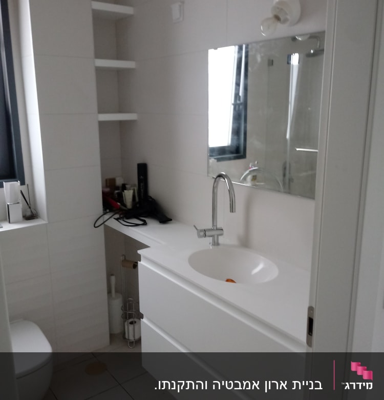 חדר אמבטיה עם כיור ומראה, מדפים ריקים